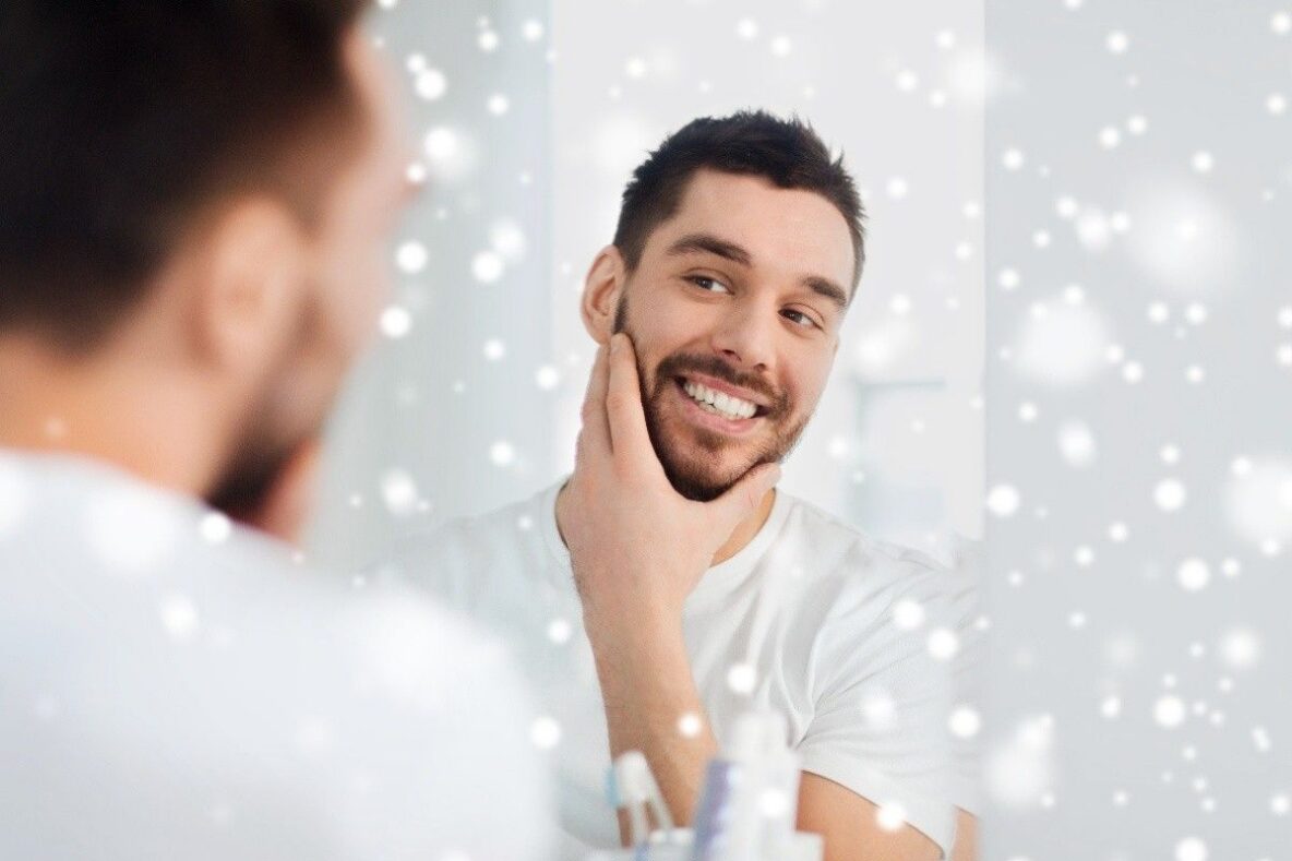 Patient smiling in mirror after dental care, representing long-term oral health in Peabody